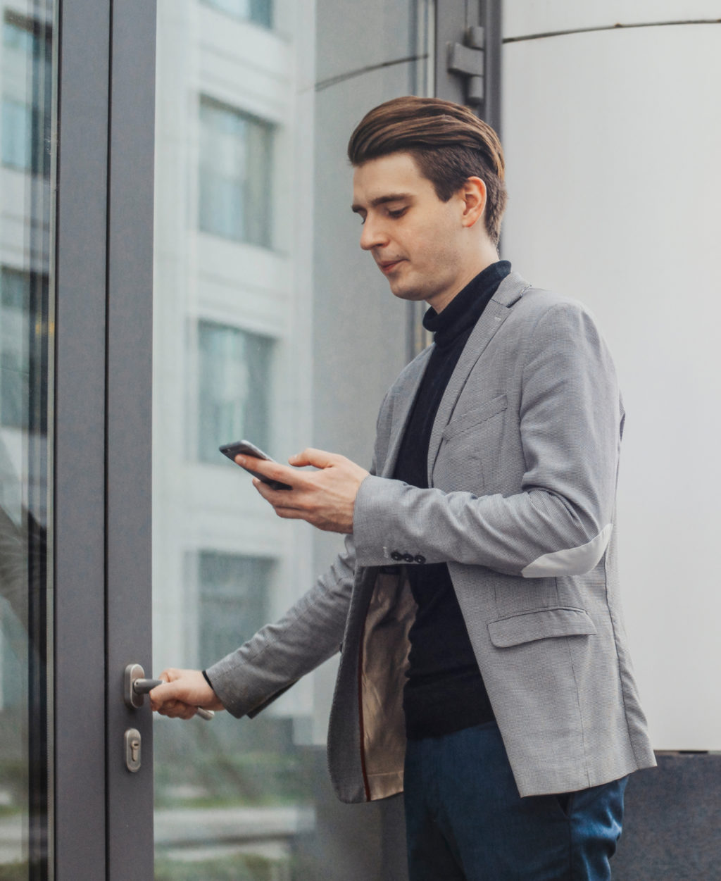man on phone opening building door
